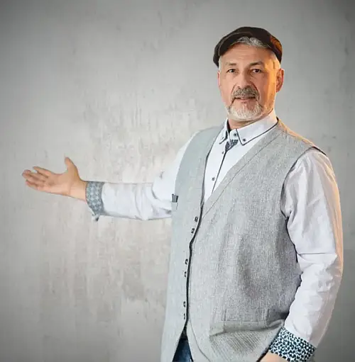 Ulrich Münchbach steht neben einer Wand und deutet einladend auf den Bereich „Einblicke & Impulse“ für KMU